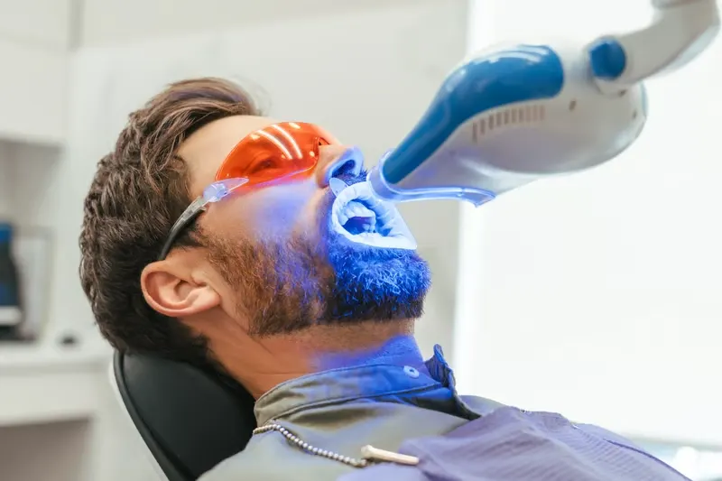 Pacjent w okularach ochronnych podczas profesjonalnego wybielania zębów światłem LED w Bel Sorriso Tandklinik Helsingborg